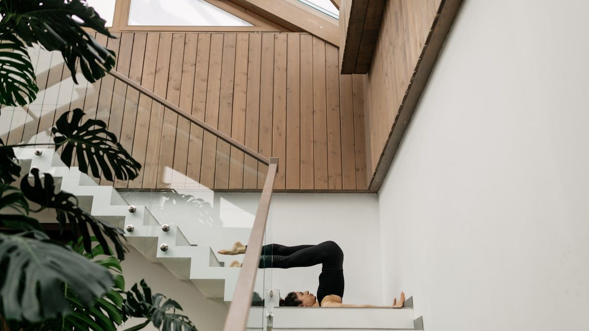 Woman performing yoga stretch on staircase, blending fitness and architecture.