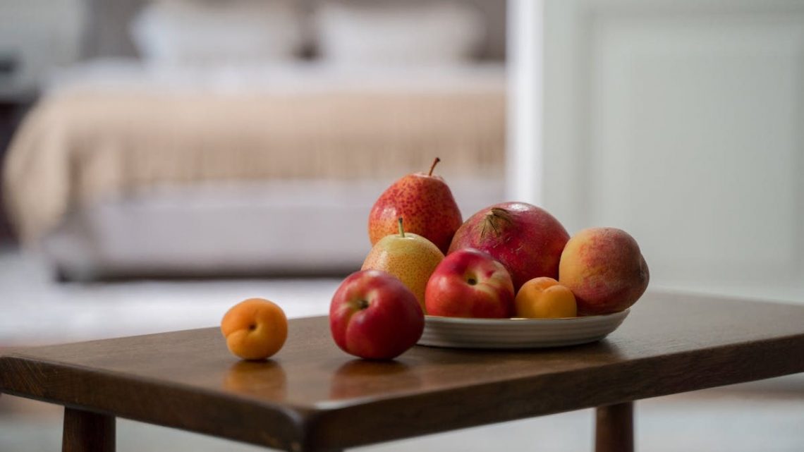 A cozy indoor still life with fresh fruits displayed on a wooden table.