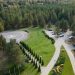 Aerial shot of a forest with a helipad, parking area, and landscaped gardens.